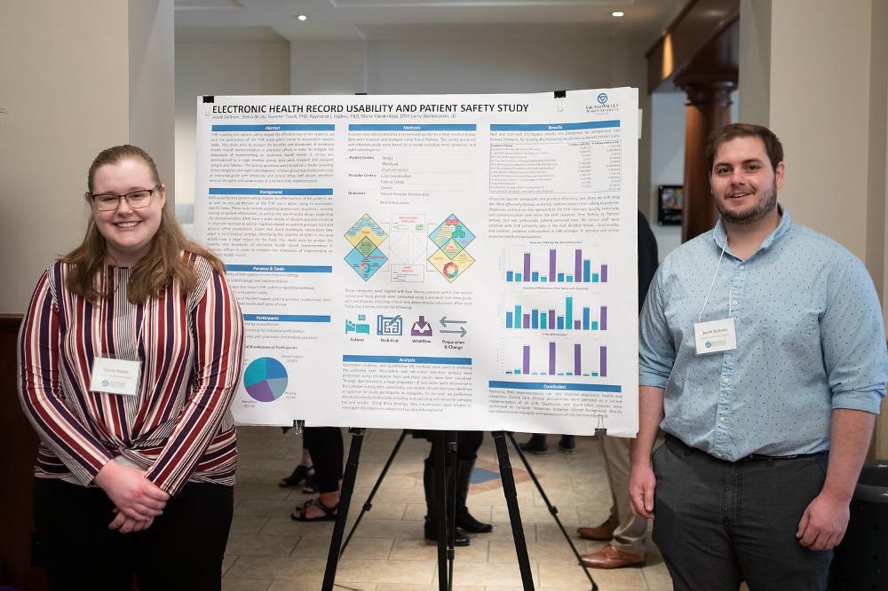 Health informatics and bioinformatics graduate students, Sierra Strutz (left) and Jacob Jackson (right), standing in front of their poster.
